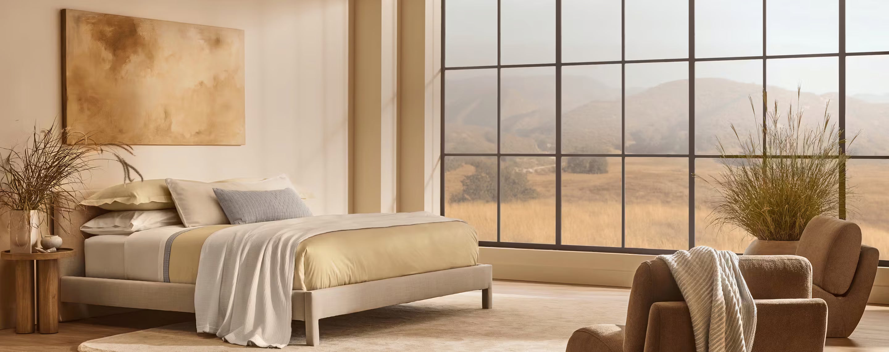 Modern bedroom with large windows showing a scenic view of mountains and fields.